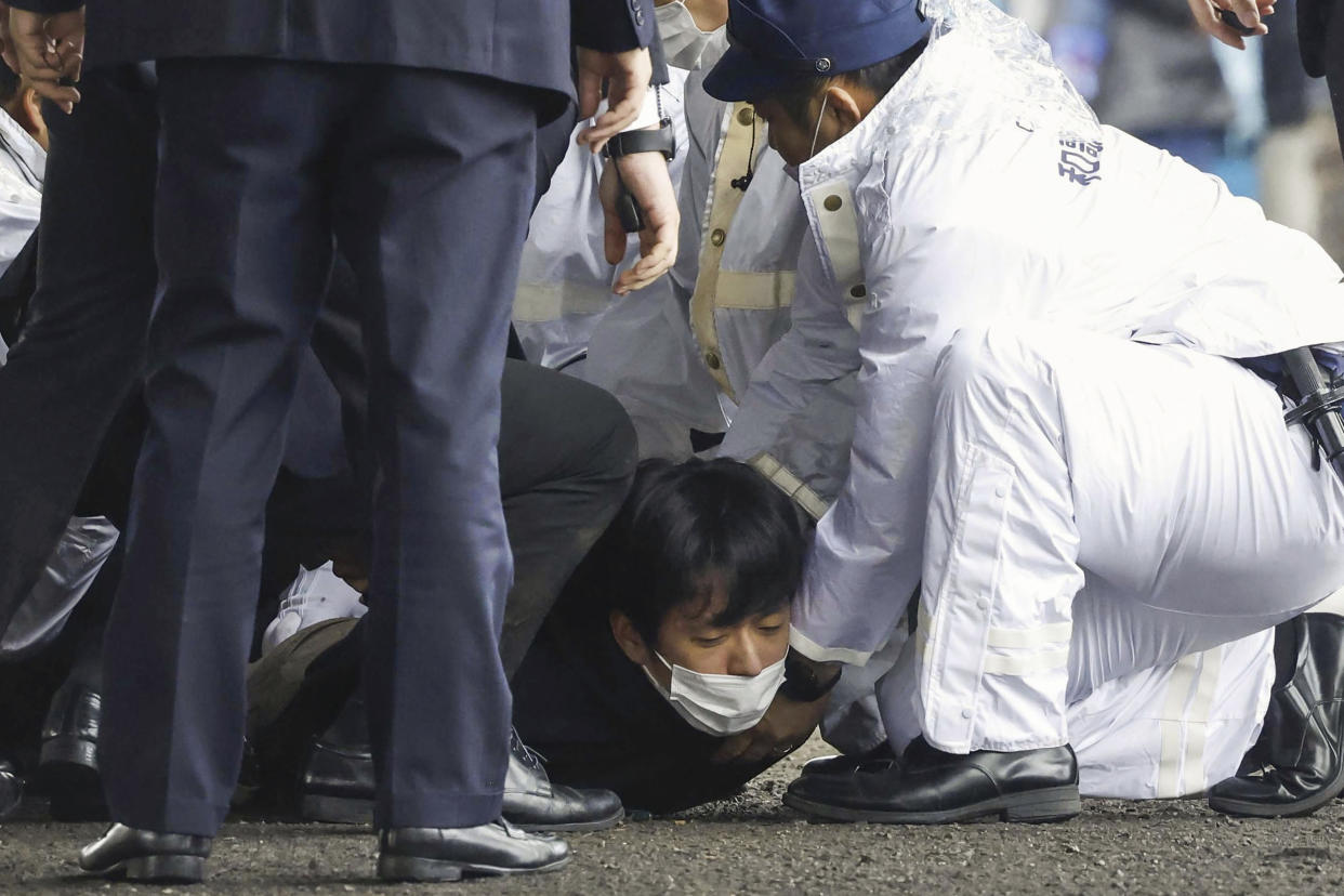 A man, on the ground, is caught after what appeared to be a smoke bomb was thrown at a port in Wakayama, western Japan Saturday, April 15, 2023. Japan’s NHK television reported Saturday that a loud explosion occurred at the western Japanese port during Prime Minister Fumio Kishida’s visit, but there were no injuries. (Kyodo News via AP)