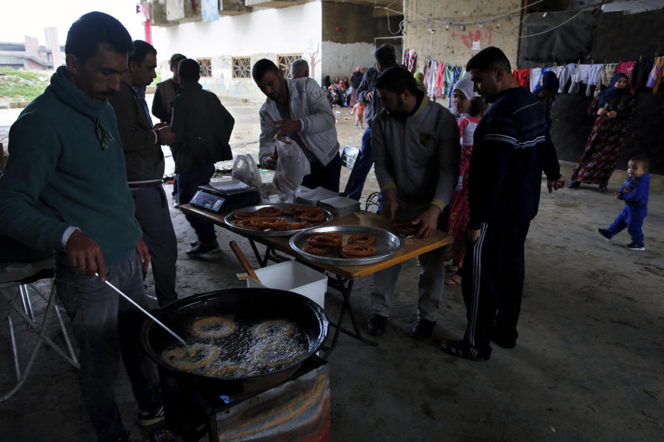 In this Tuesday, Dec. 18, 2018, photo, a Syrian refugee man, left, prepares Syrian sweets to be sold in Ouzai refugee compound, in the southern port city of Sidon, Lebanon. A much touted Russian initiative to facilitate the return of Syrian refugees has fizzled out, with the return of only about 114,000 Syrians - out of more than 5 million in the region and Europe. In Lebanon, which hosts the highest ratio of refugees per capita, most of the estimated 1.2 million Syrians say the intend to stay put, citing economic concerns, ongoing fighting and destroyed homes. (AP Photo/Bilal Hussein)