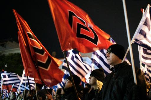 Unos miembros del partido de extrema derecha Amanecer Dorado sostienen banderas en una manifestación en Atenas, el 1 de febrero de 2014 (AFP | Louisa Gouliamaki)