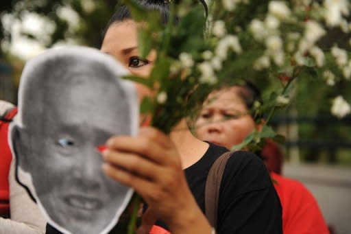 Thai activists hold flowers during a gathering held outside Bangkok Remand Prison where Ampon Tangnoppakul died on May 8. Hundreds of people have gathered in Bangkok to mourn the death of a Thai grandfather imprisoned for defaming the monarchy as an autopsy suggested liver cancer was the cause