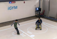 In this Nov. 17, 2019, photo provided by the University of Michigan, brothers Darren Kreps, left, and Bryan Kreps play a game modeled after soccer and air hockey using the iGYM system at the university in Ann Arbor, Mich. A University of Michigan research team has created iGYM, an augmented reality system that allows people with different levels of mobility to play and exercise together. (Roger Hart/University of Michigan via AP)