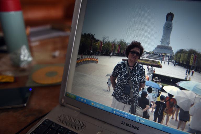 Activist Xu Xiangyu is seen posing for a photo in front of the Buddha statue at the Nanshan Temple on China's southern Hainan island, during a forced vacation in March 2011