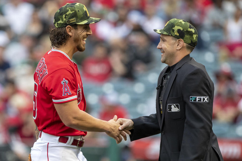 Los Angeles Angels starting pitcher Michael Lorenzen, left, smiles as he meets with home plate umpire David Rackley, who was checking the pitcher for foreign substances during the first inning of the team's baseball game against the Oakland Athletics in Anaheim, Calif., Saturday, May 21, 2022. (AP Photo/Alex Gallardo)