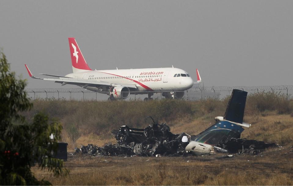 <p>Remains of Bangladesh’s US-Bangla Flight BS211 lies on the ground as a plane takes off from Tribhuvan International Airport in Kathmandu, Nepal, March 13, 2018. (Photo: Niranjan Shreshta/AP) </p>