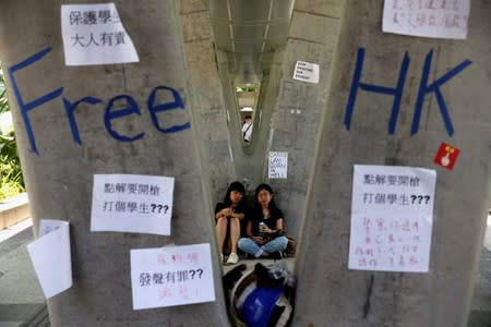 People sit next to posters and signs placed following protests against the proposed extradition bill, in Hong Kong, China