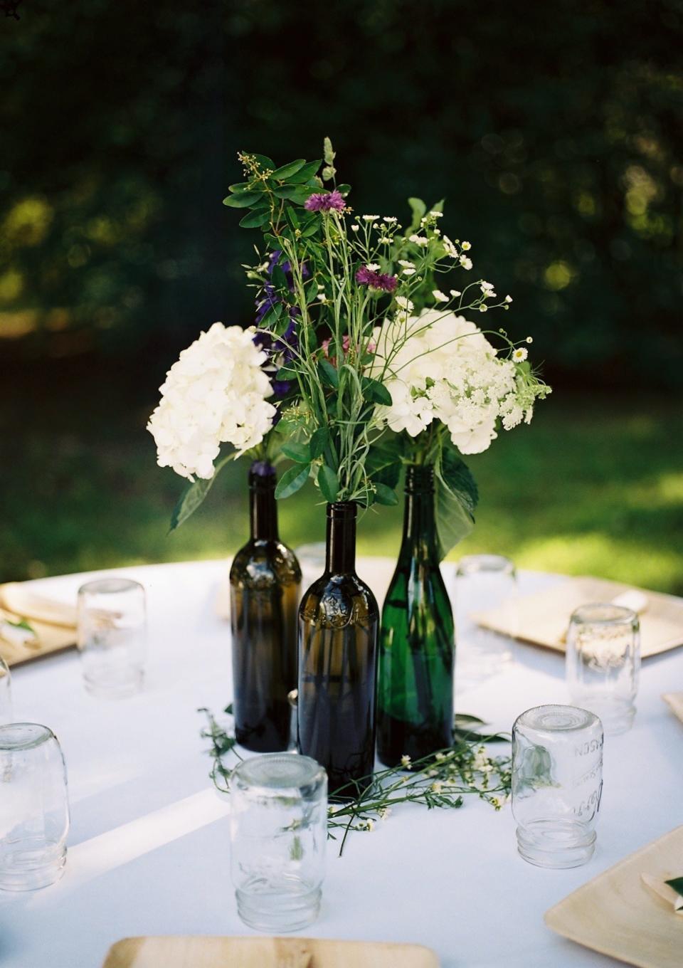 Three vases full of flowers sit on a white table.