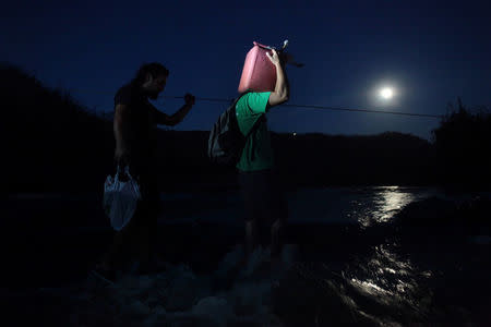 A local resident carries a gasoline can as he crosses a river using a cable after Hurricane Maria destroyed the town's bridge in San Lorenzo, Morovis, Puerto Rico, October 4, 2017. REUTERS/Alvin Baez