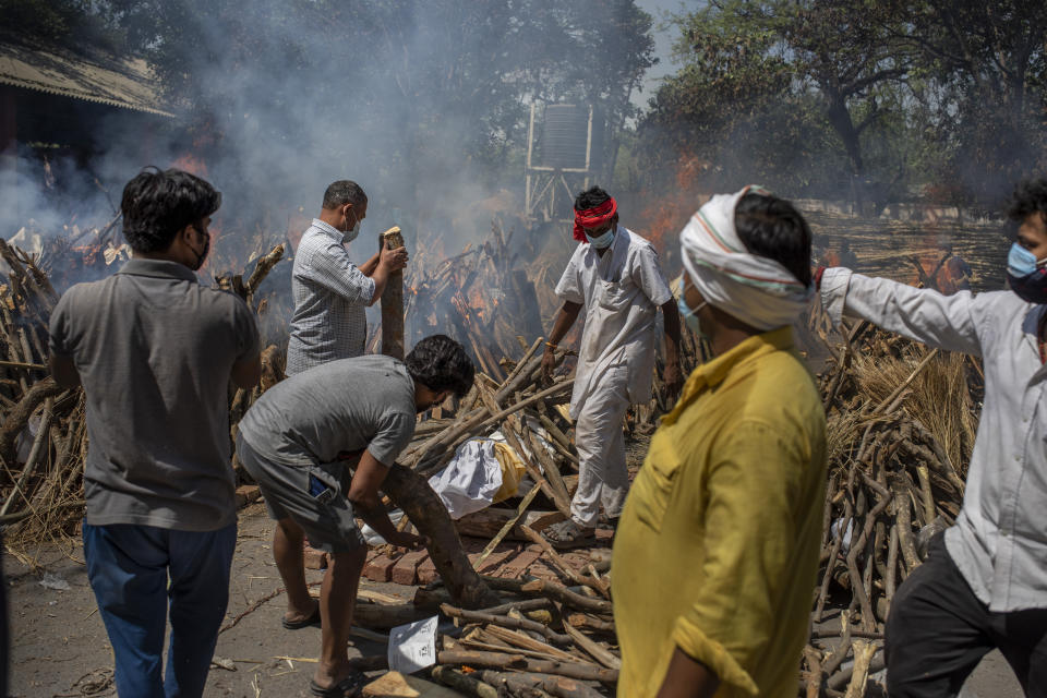 Members of a family of COVID-19 victim prepare funeral pyre for deceased member as multiple funeral pyres of those who died of COVID-19 are seen at a crematorium in New Delhi, India, Saturday, April 24, 2021. Delhi has been cremating so many bodies of coronavirus victims that authorities are getting requests to start cutting down trees in city parks, as a second record surge has brought India's tattered healthcare system to its knees. (AP Photo/Altaf Qadri)