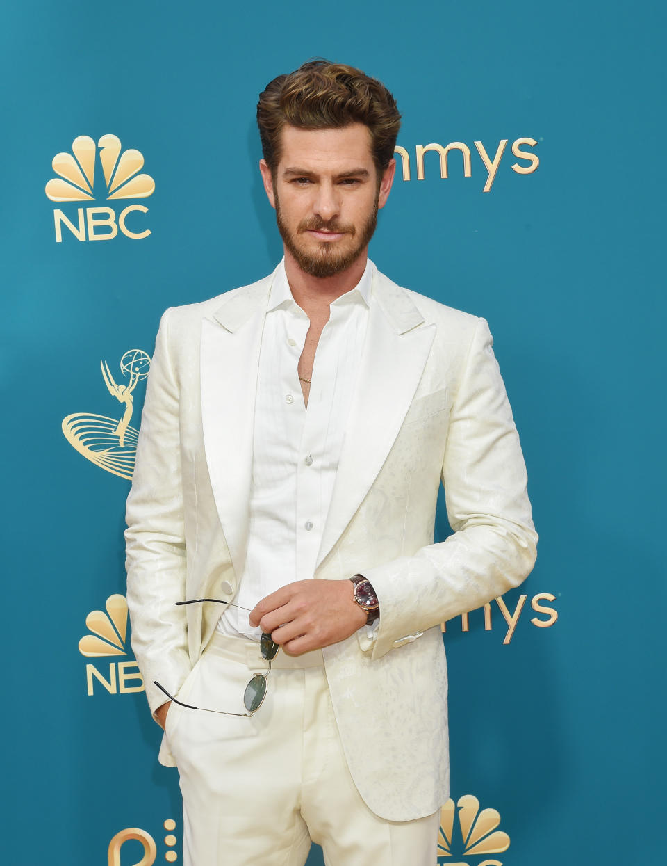 Andrew in a light-colored suit and holding sunglasses