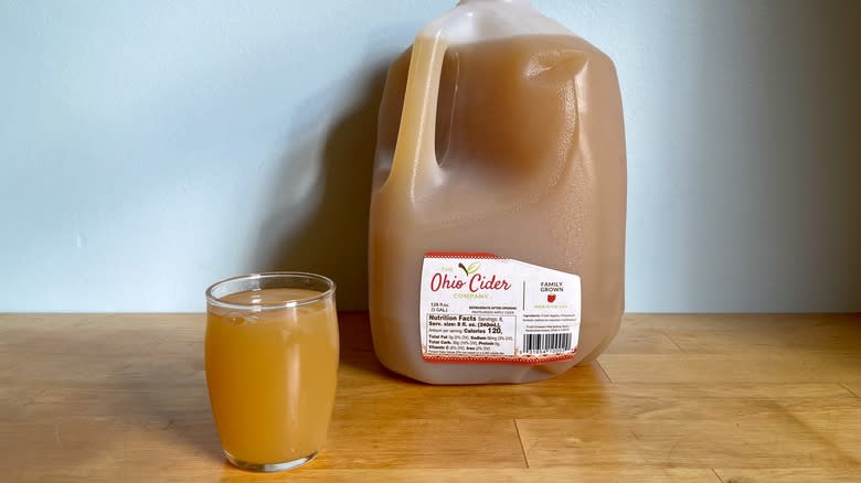Gallon cider with drink in glass cup