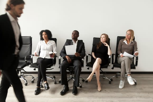 Man walking by four people seated in chairs.