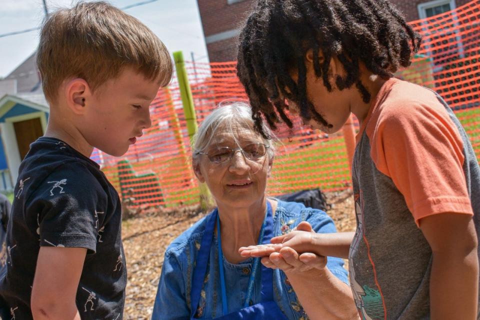 Rainbow Station Preschool Director Roberta Patterson helps her students find “roly-poly” bugs during outside playtime.