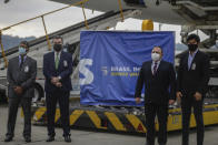 India's Ambassador to Brazil Suresh Reddy, left, Brazil's Foreign Minister Ernesto Araujo, second left, Brazil's Heath Minister Eduardo Pazuello, second from right, and Brazil's Communications Minister Fabio Faria stand in front of a container of vaccines for COVID-19, produced by Oxford/AstraZeneca, after it arrived from India at the international airport in Sao Paulo, Brazil, Friday, Jan. 22, 2021. (AP Photo/Marcelo Chello)