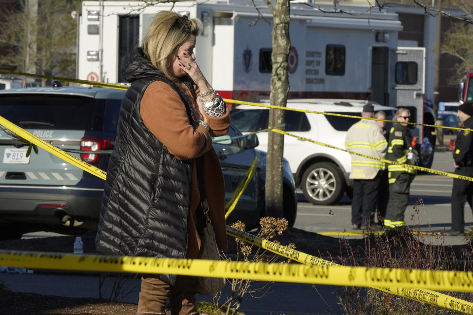 A woman is tearful while standing behind police tape at a scene where an SUV drove into an Apple store, Monday, Nov. 21, 2022, in the Derby Street Shops, in Hingham, Mass. One person was killed and multiple others were injured Monday when the SUV crashed into the store, authorities said. (AP Photo/Steven Senne)