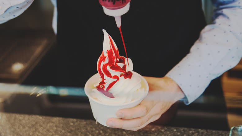 adding strawberry sauce to frozen yogurt