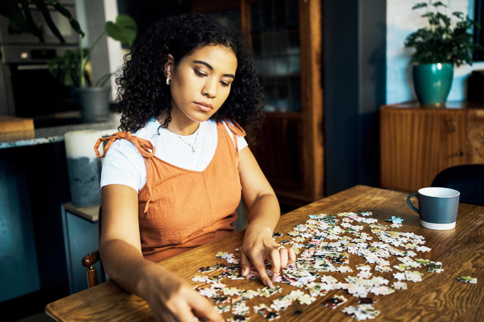 Woman working on a puzzle at a table in the living room. (Getty Images)
