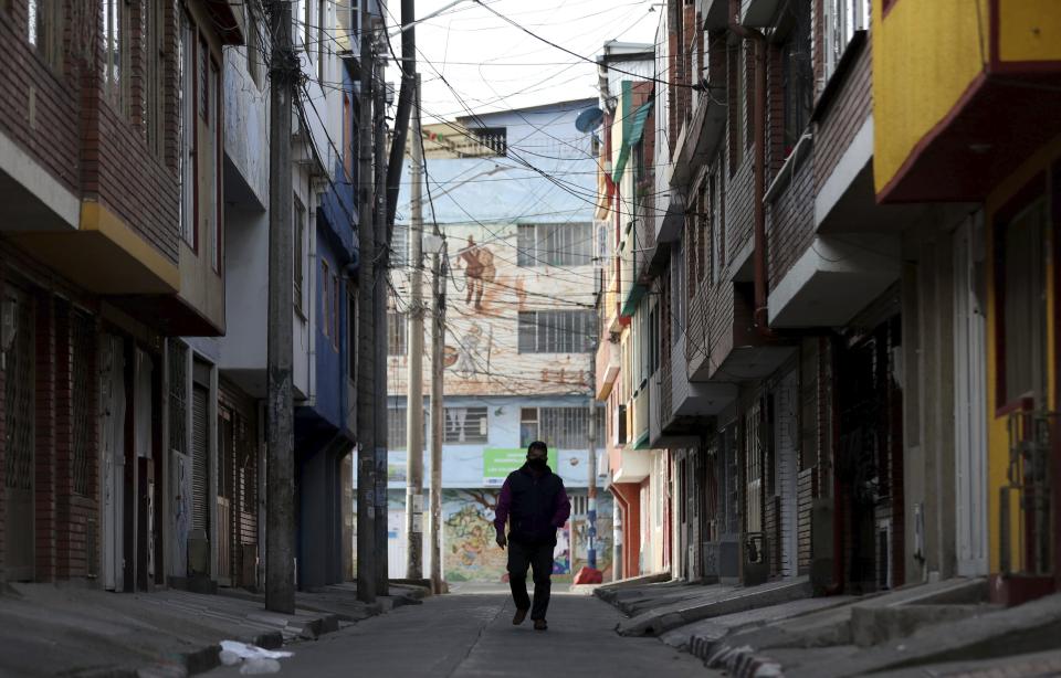 A man walks to work in Bogota, Colombia, Wednesday, Aug. 5, 2020. While restrictions to curb COVID-19 have been lifted in many places, a nationwide stay-at-home order remains in effect in Colombia more than four months after taking effect. (AP Photo/Fernando Vergara)