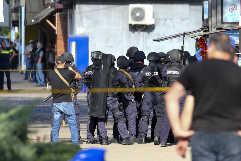 Georgian police gather at a bank where an armed assailant took several people hostage in the town of Zugdidi in western Georgia, Wednesday, Oct. 21, 2020. An armed assailant took several people hostage at a bank in the ex-Soviet nation of Georgia on Wednesday, authorities said. The Georgian Interior Ministry didn't immediately say how many people have been taken hostage in the town of Zugdidi in western Georgia, or what demands the assailant has made. Police sealed off the area and launched an operation "to neutralize the assailant," the ministry said in a statement. (AP Photo/Zurab Tsertsvadze)