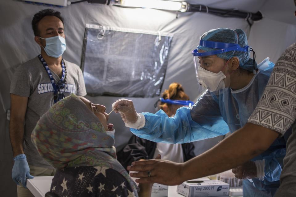 FILE - Medical staff of the National Health Organization (EODY) conduct tests for the new coronavirus from migrants in Moria refugee camp on the northeastern Aegean island of Lesbos, Greece, on Friday, Sept. 4, 2020. A major testing and contact-tracing operation at Greece's largest migrant camp on the eastern island of Lesbos has so far detected 17 confirmed cases of COVID-19 infection among the 12,500 people living in the overcrowded facility, officials said on Tuesday, Sept. 8, 2020. (AP Photo/Panagiotis Balaskas, File)