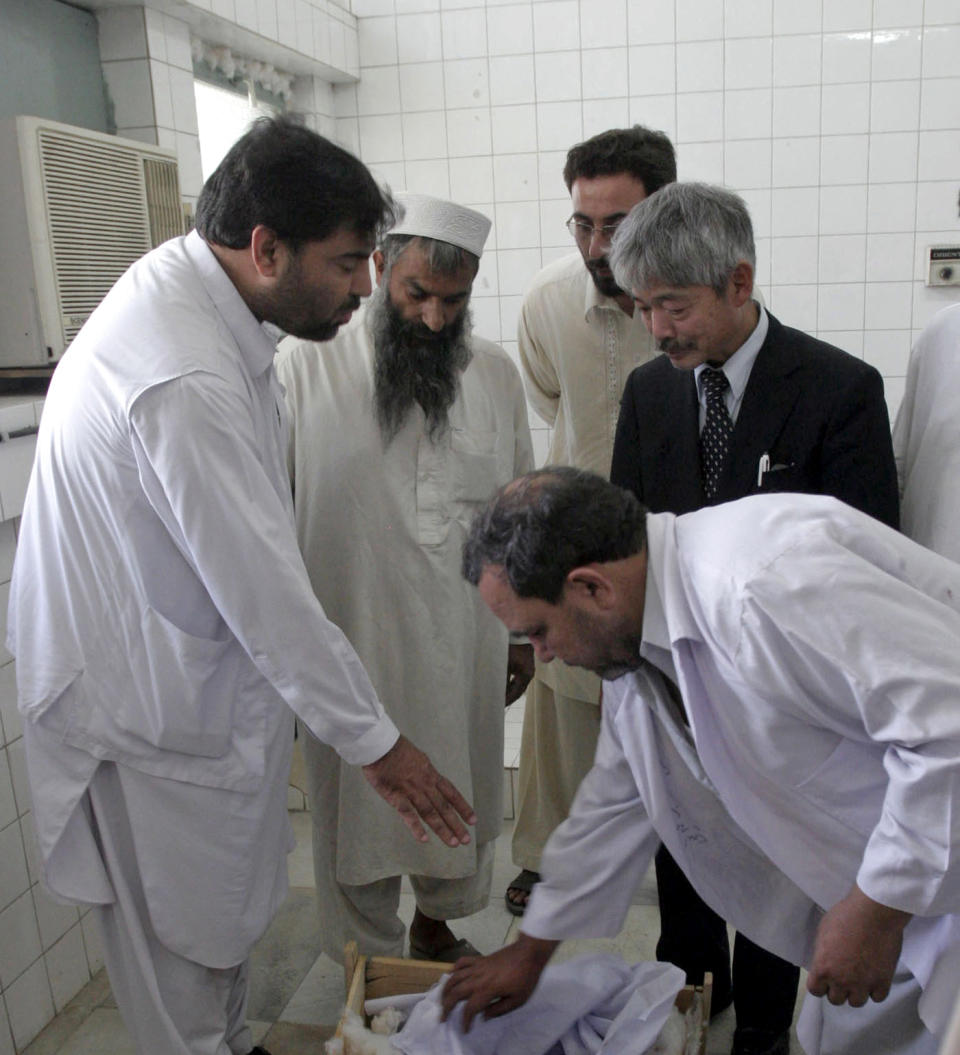 FILE-In this Aug. 28, 2008, photo, Afghan hospital officials and the Japanese doctor Tetsu Nakamura, second right in black suit, looks on the Japanese aid worker Kazuya Ito, at the hospital in Jalalabad city the provincial capital of Nangarhar province. The Japanese physician and aid worker in eastern Afghanistan died of his wounds after an attack Wednesday, Dec. 4, 2019, that also killed five Afghans, including the doctor’s bodyguards, the driver and a passenger, a hospital spokesman said. (AP Photo/Rahmat Gul, File)