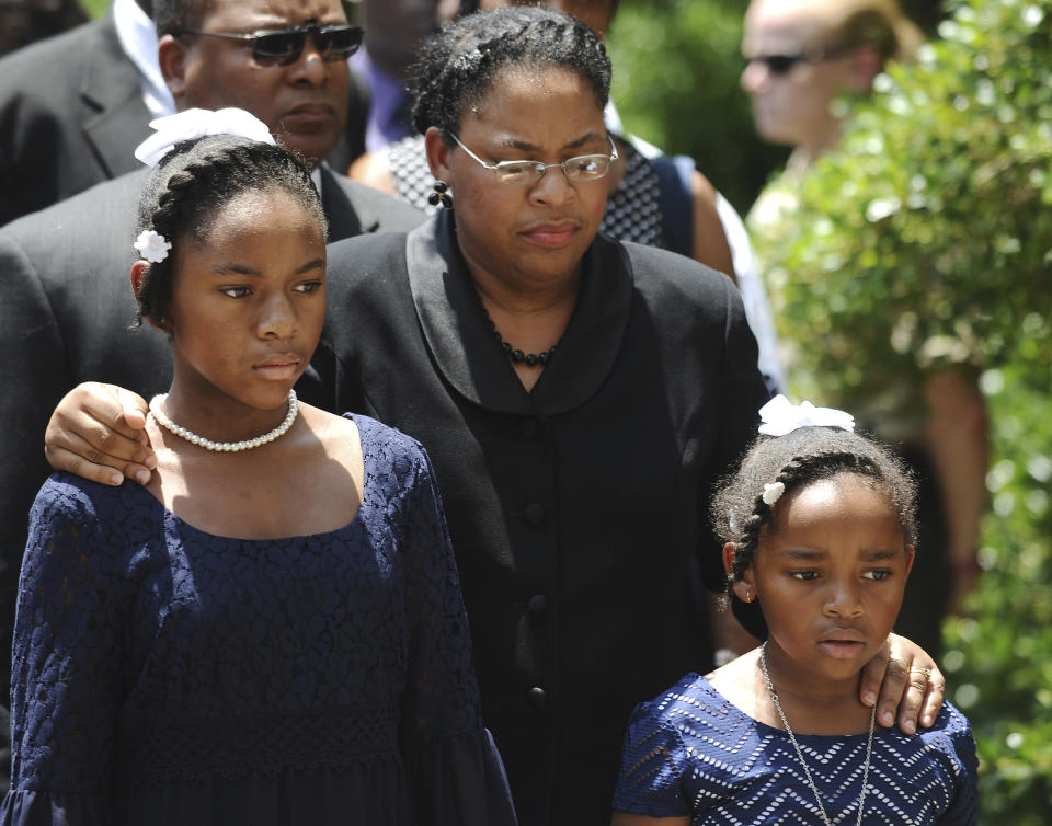 FILE - In this June 24, 2015, file photo Sen. Clementa Pinckney's wife Jennifer Pinckney, center, and her daughters, Eliana, left, and Malana, right, follow his casket into the South Carolina Statehouse in Columbia, S.C. The Rev. Clementa Pinckney, was one of the nine killed by Dylann Roof, who sat through 45 minutes of Bible study at the church before firing shots. Pinckney and her daughter, Malana, were in the late reverend’s office when they heard gun shots in another room. (AP Photo/Rainier Ehrhardt, File)