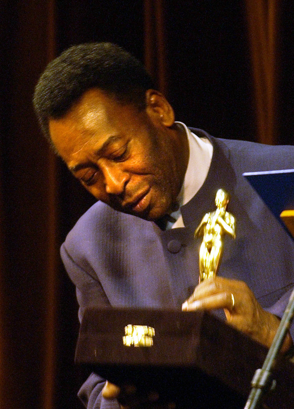 FILE - Brazilian soccer legend Pelé looks at a statue given by the Rio de Janeiro Gov. Rosinha Matheus, at the Municipal Theater in Rio de Janeiro, Monday, June 21, 2004. The recognition was given during the premier of the movie "Pelé Eterno." Pelé, who won a record three World Cups and became one of the most commanding sports figures of the last century, died in Sao Paulo on Thursday, Dec. 29, 2022. He was 82. (AP Photo/Victor R. Caivano, File)