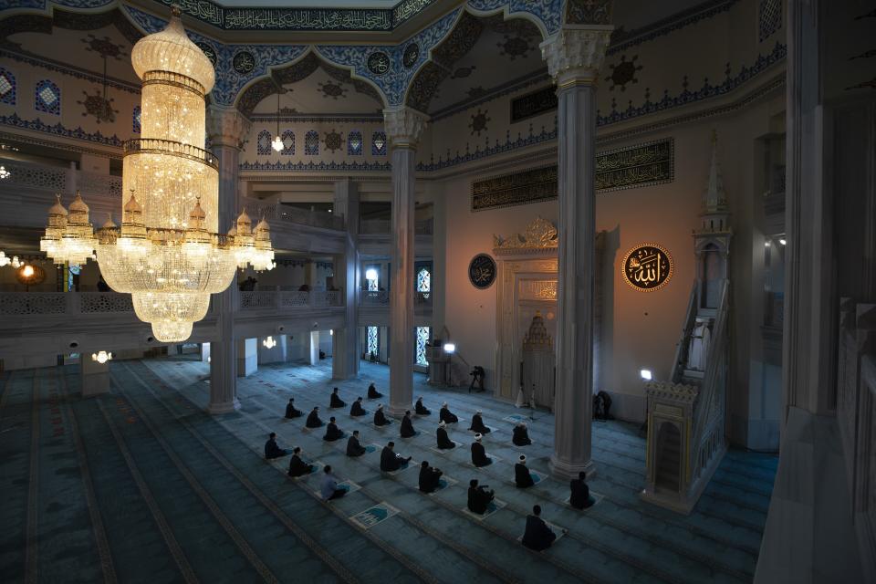 Mullahs wearing masks to help stop the spread of the coronavirus wait for Eid al-Adha prayer while maintaining social distancing at the almost empty main Mosque in Moscow, Russia, Friday, July 31, 2020. Muslims worldwide marked the the Eid al-Adha holiday over the past days amid a global pandemic that has impacted nearly every aspect of this year's celebrations. (AP Photo/Alexander Zemlianichenko)