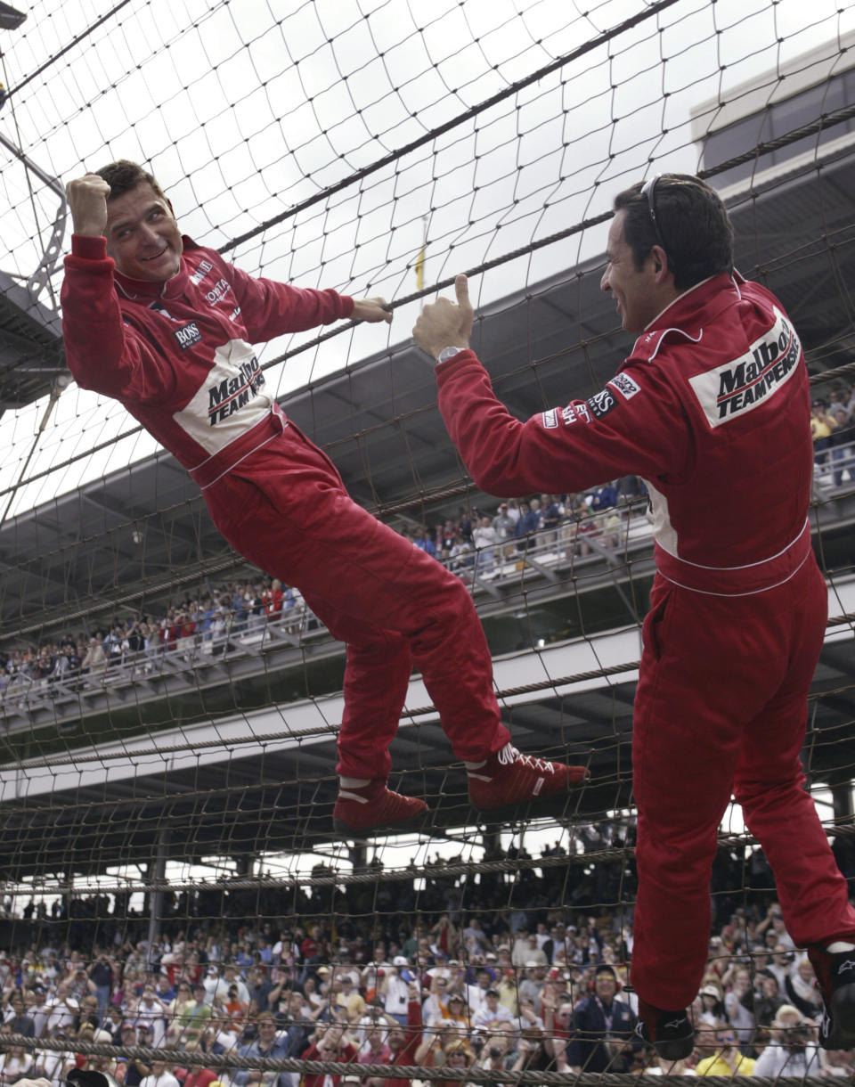 FILE - Indianapolis 500 winner Gil de Ferran, left, climbs the fence with Penske teammate Helio Castroneves, who finished second, after the auto race at Indianapolis Motor Speedway on May 25, 2003, in Indianapolis. De Ferran, holder of the closed-course land speed record and 2003 Indy 500 winner, died Friday, Dec. 29, 2023, while racing with his son at The Concourse Club in Florida, multiple former colleagues confirmed to The Associated Press. He was 56. (AP Photo/Tom Strattman, File)