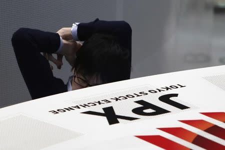 An employee of the Tokyo Stock Exchange (TSE) stretches his body as he works at the bourse at TSE in Tokyo March 13, 2015. REUTERS/Yuya Shino