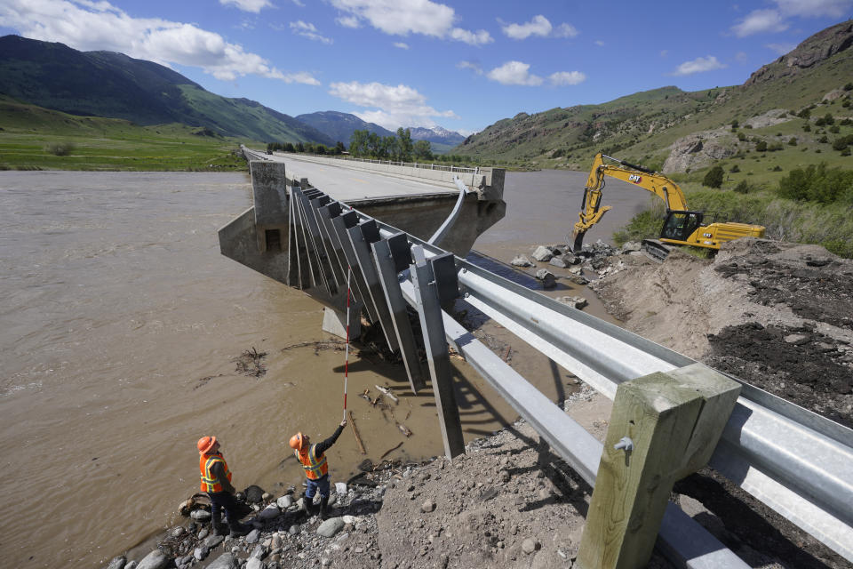 Highway workers inspect a washed out bridge along the Yellowstone River Wednesday, June 15, 2022, near Gardiner, Mont. Yellowstone National Park officials say more than 10,000 visitors have been ordered out of the nation's oldest national park after unprecedented flooding tore through its northern half, washing out bridges and roads and sweeping an employee bunkhouse miles downstream. (AP Photo/Rick Bowmer)