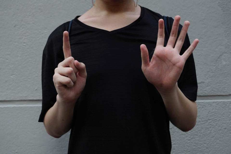 A protester gestures with five fingers, signifying the "Five demands and not one less" outside the Prince Edward subway station in Hong Kong Monday, Aug. 31, 2020. Aug. 31 is the first anniversary of police raid on Prince Edward subway station which resulted in widespread images of police beating people and drenching them with pepper spray in subway carriages. (AP Photo/Vincent Yu)