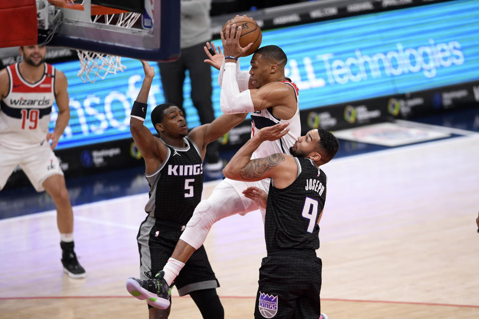 Washington Wizards guard Russell Westbrook, center, goes to the basket between Sacramento Kings guard De'Aaron Fox (5) and guard Cory Joseph (9) during the first half of an NBA basketball game, Wednesday, March 17, 2021, in Washington. (AP Photo/Nick Wass)