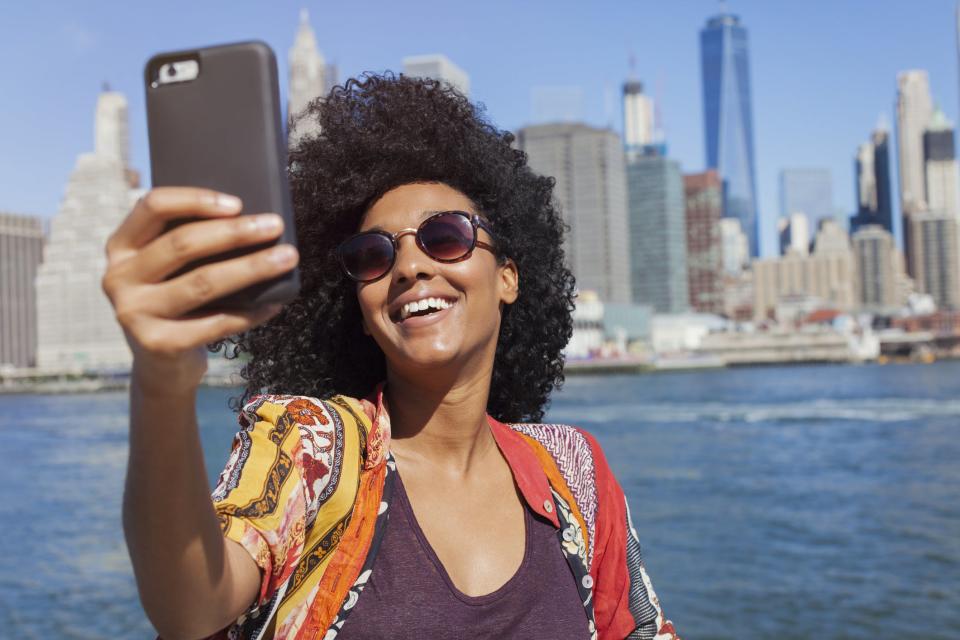 Woman taking selfie with NYC skyline in background