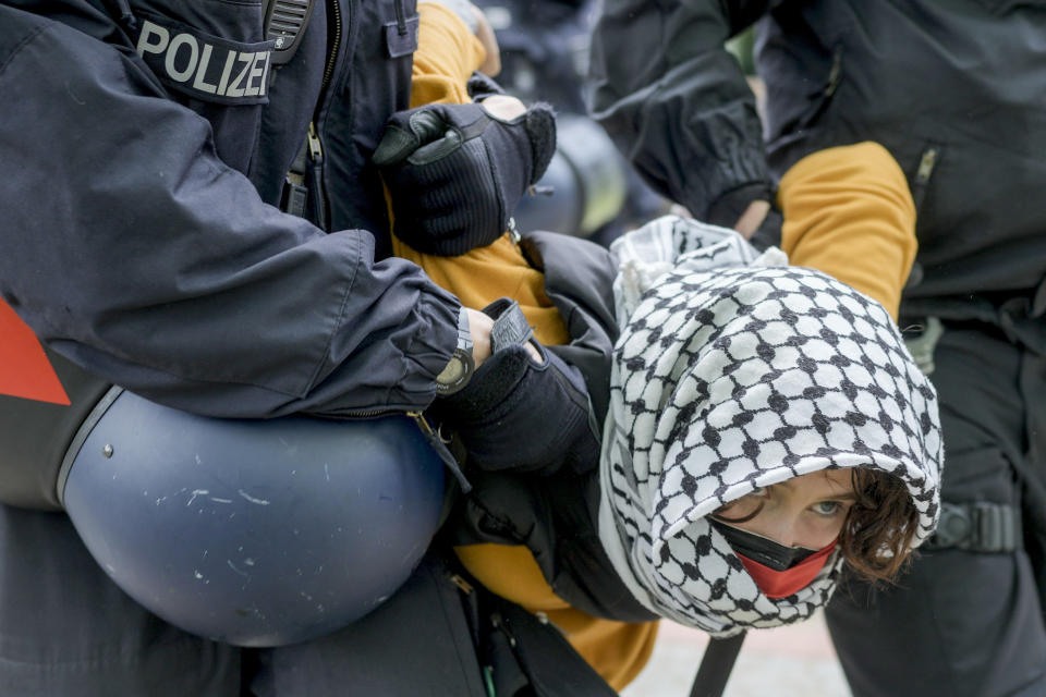 Una mujer es retirada por policías en una protesta propalestina del grupo "Coalición Estudiantil Berlín" en el patio de teatro de la Universidad Libre de Berlín, en Berlín, el martes 7 de mayo de 2024. (AP Foto/Markus Schreiber)