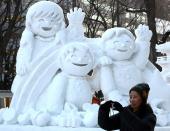 A woman takes photos of ice sculptures ahead of the 60th Sapporo Snow Festival at Odori Park in 2009 in Sapporo, Japan.