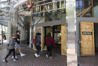 Shoppers walk into Pioneer Place shopping mall still protected by wooden panels to prevent windows being smashed by on-going protests in Portland, Ore., on Saturday, June 5, 2021. Until a year ago, the city was best known nationally for its ambrosial food scene, craft breweries and “Portlandia” hipsters. Now, months-long protests following the killing of George Floyd, a surge in deadly gun violence, and an increasingly visible homeless population have many questioning whether Oregon’s largest city can recover. (AP Photo/Paula Bronstein)