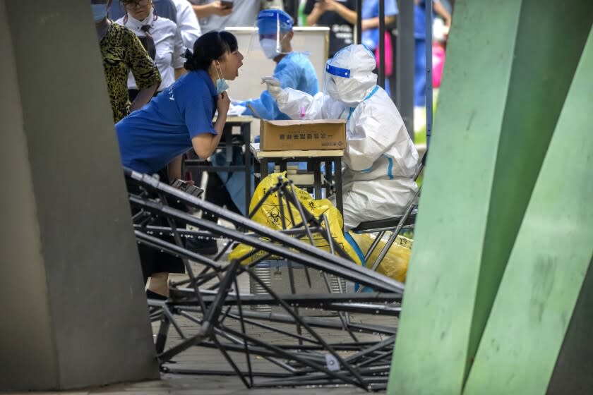 A worker wearing a protective suit swabs a woman's throat for a COVID-19 test at a coronavirus testing site in Beijing, Wednesday, July 6, 2022. Residents of parts of Shanghai and Beijing have been ordered to undergo further rounds of COVID-19 testing following the discovery of new cases in the two cities, while additional restrictions remain in place in Hong Kong, Macao and other cities. (AP Photo/Mark Schiefelbein)