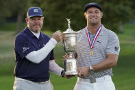 Bryson DeChambeau, of the United States, right, holds up the winner's trophy with his caddie, Tim Tucker, after winning the US Open Golf Championship, Sunday, Sept. 20, 2020, in Mamaroneck, N.Y. (AP Photo/John Minchillo)
