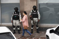 FILE - A woman walks past members of the National Guard patrolling downtown Fresnillo after a series of armed clashes between criminal groups, in Zacatecas state, Mexico, July 13, 2021. Mexico’s President Andres Manuel Lopez Obrador has begun exploring plans to side-step congress to hand formal control of the National Guard to the army. That has raised concerns, because Lopez Obrador won approval for creating the force in 2019 by pledging in the constitution that it would be under nominal civilian control and that the army would be off the streets by 2024. (AP Photo/Marco Ugarte, File)