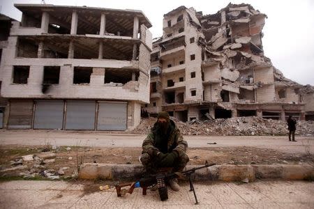 A member of forces loyal to Syria's President Bashar al-Assad sits near damaged buildings in Aleppo's Salaheddine district, Syria December 16, 2016. REUTERS/Omar Sanadiki