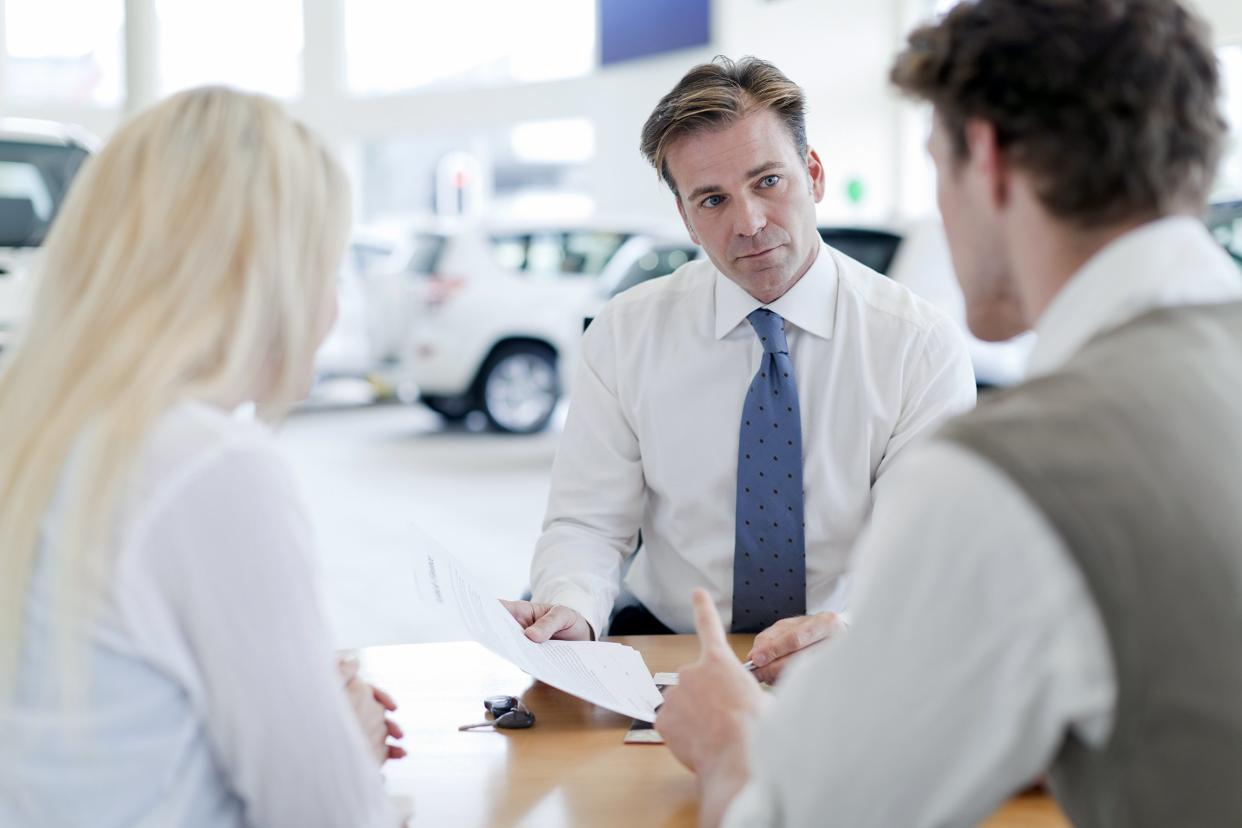 car salesman with customers at desk