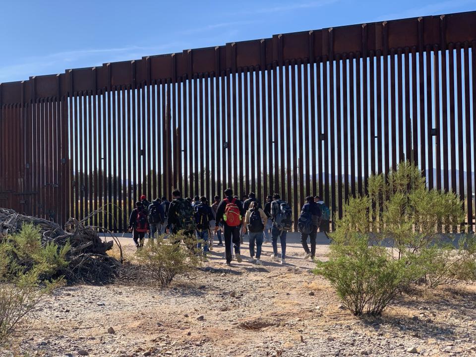 A group of migrants from India that crossed the border at Organ Pipe Cactus National Monument in Arizona walk along the border enforcement road next to the breached border fence on Nov. 1, 2023.