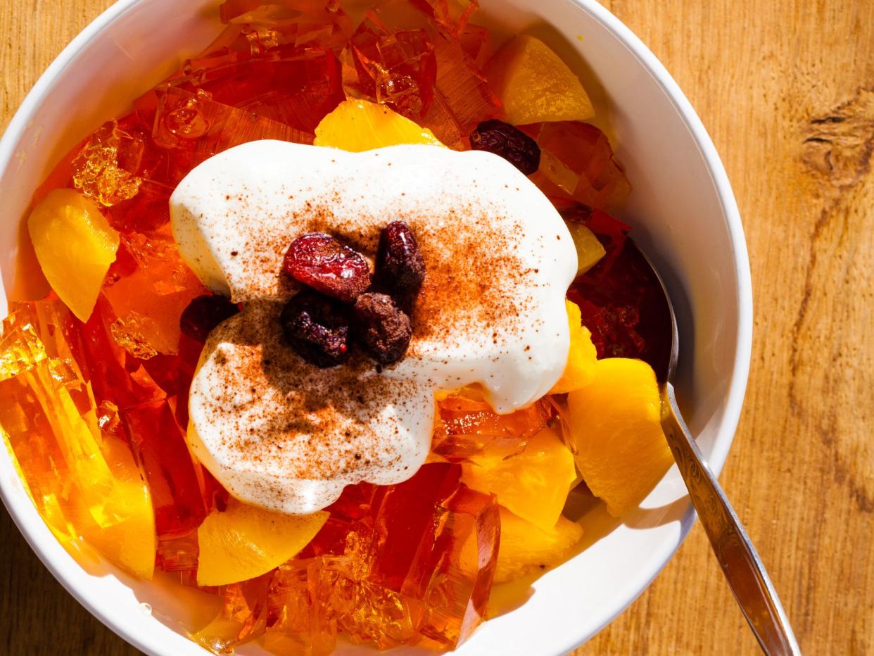 Delicious sweet jelly dessert in bowl with whipped cream and raisin cranberry on wooden table