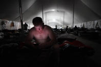 Bryan Willis, of Stilwell, Okla., an electrical worker for Ozarks Electric, looks at his phone before going to bed in a tent city for electrical workers in Amelia, La., Thursday, Sept. 16, 2021. When Hurricane Ida was brewing in the Gulf of Mexico, the grass was chest high and the warehouse empty at this lot in southeastern Louisiana. Within days, electric officials transformed it into a bustling “tent city” with enormous, air-conditioned tents for workers, a gravel parking lot for bucket trucks and a station to resupply crews restoring power to the region. (AP Photo/Gerald Herbert)