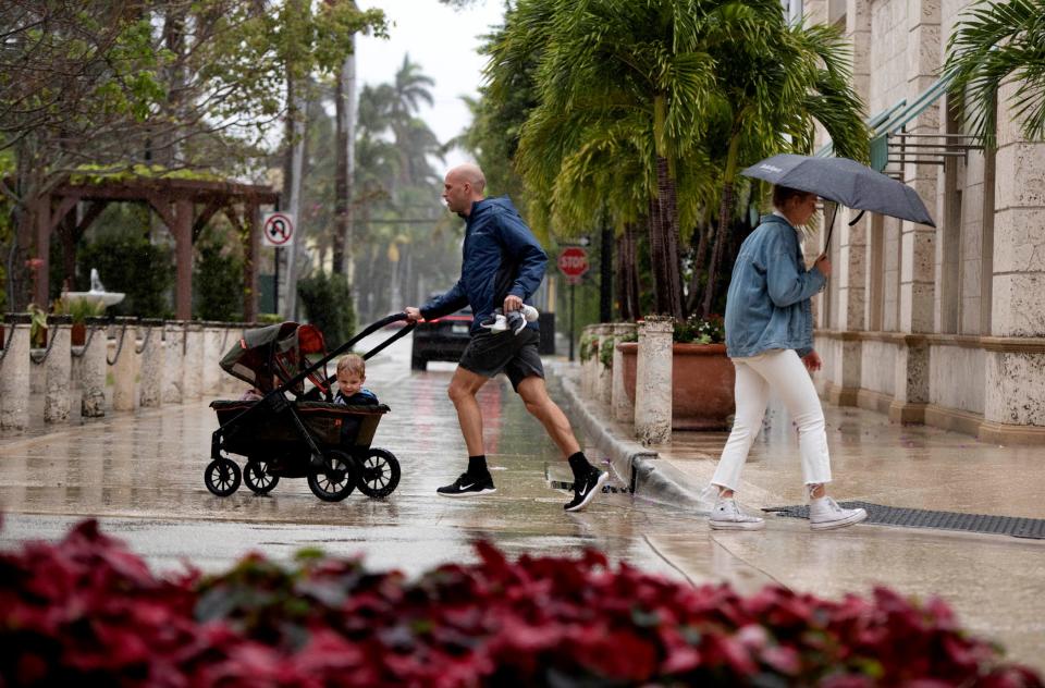 Pedestrians brave cool raining weather along Worth Avenue at Hibiscus Avenue in Palm Beach December 28, 2023.