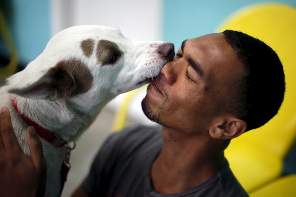 Mansai Conner is licked by a dog on the opening day of Dog Cafe, a coffee shop where people can adopt shelter dogs in Los Angeles. REUTERS/Lucy Nicholson