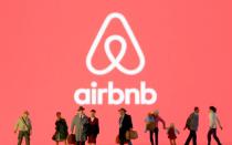 FILE PHOTO: Small toy figures are seen in front of diplayed Airbnb logo