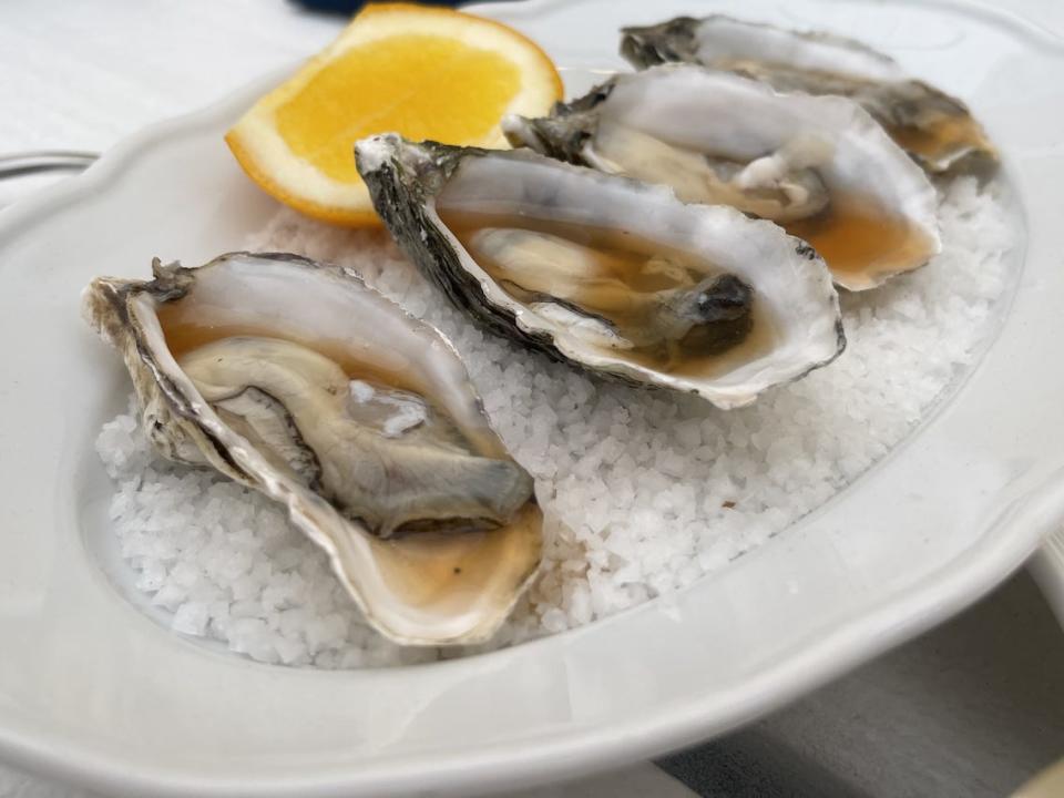 four oysters on plate with citrus