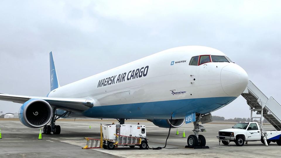 A Maersk Air Cargo aircraft with light-blue accents at rest on the tarmac, photo from front, steps to cockpit on the side.