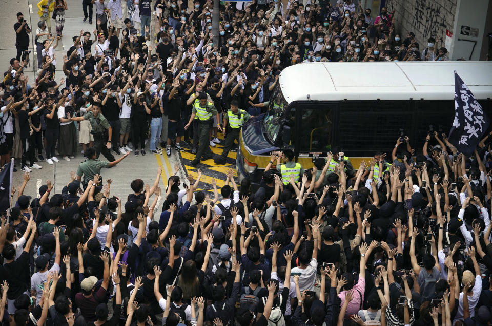 FILE - Supporters surround a police bus carrying political activist Edward Leung as it leaves the High Court, after Leung sentenced to six years in prison for his part in a violent nightlong clash with police on Oct. 9, 2019, in Hong Kong. Leung, who coined the now-banned slogan "Liberate Hong Kong, Revolution of our Times," was released from prison Wednesday, Jan. 19, 2022, after spending four years behind bars for rioting in 2016. (AP Photo/Vincent Yu, File)